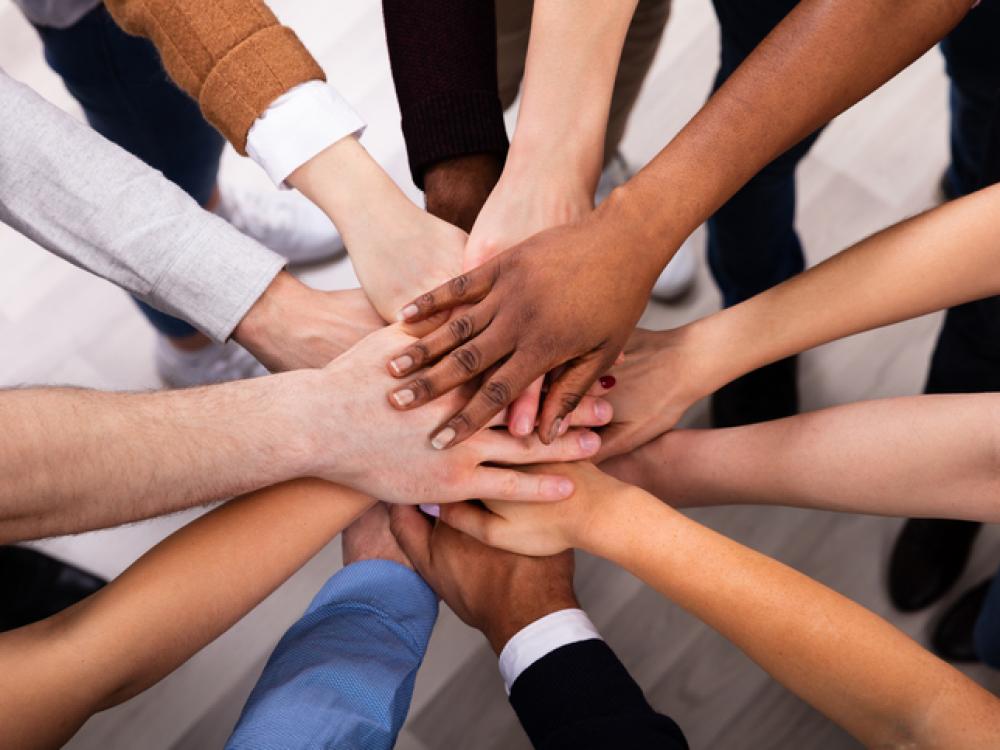 hands of different colors stacked together, some showing business clothing