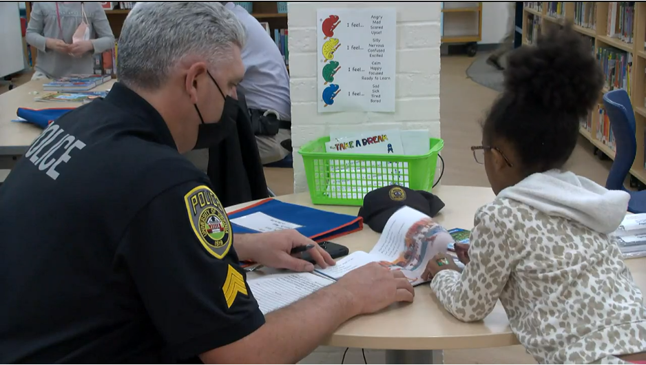 UPD officer works with a Greer Elementary School student learning to read