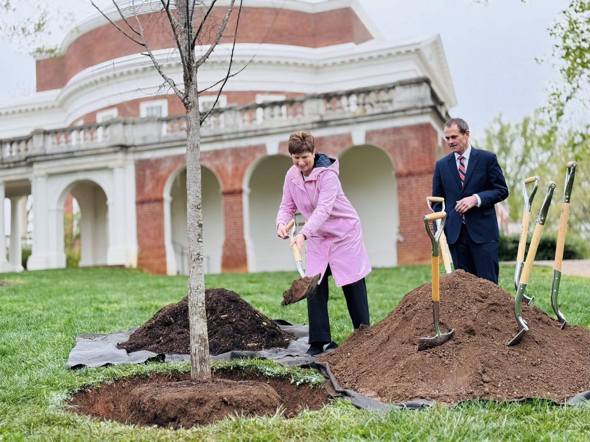 Colette Sheehy shoveling dirt with President Jim Ryan on the East Rotunda while planting a tree