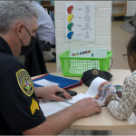 UPD officer works with a Greer Elementary School student learning to read
